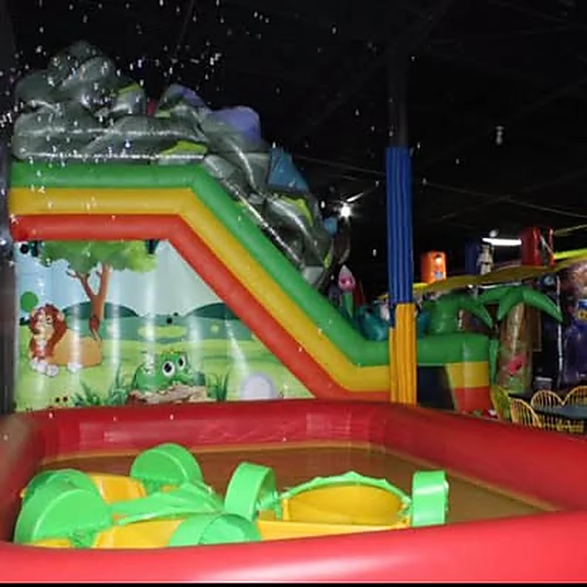 Tobogán inflable de jungla que desemboca en una piscina inflable roja.